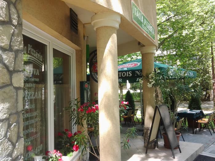 A pizzéria fedett teraszrésze napernyőkkel és virágokkal